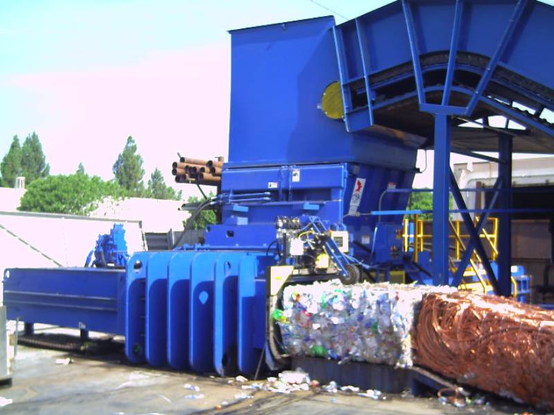 A blue machine is next to a pile of trash.