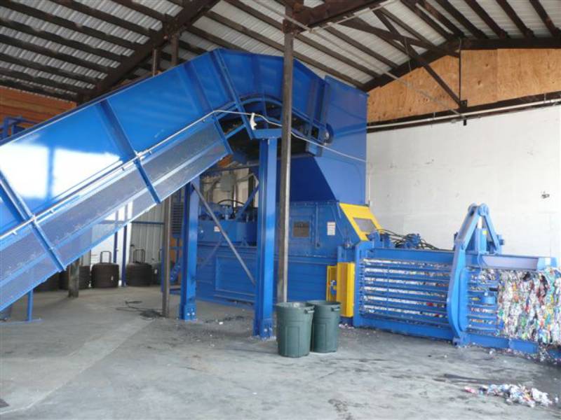 A blue machine in a warehouse with trash cans.