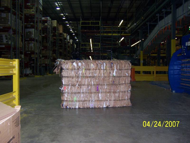 A large stack of cardboard boxes in an industrial warehouse.