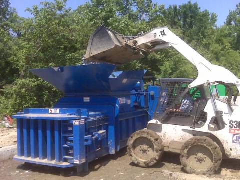 A blue machine is being loaded with wood
