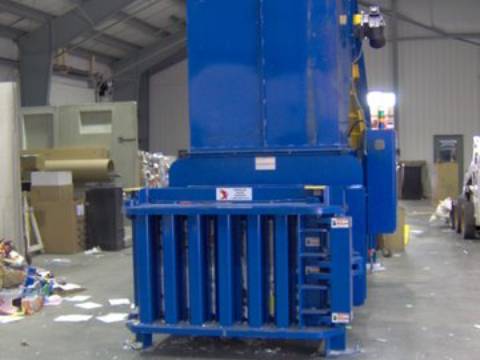 A blue machine is in the middle of a warehouse.
