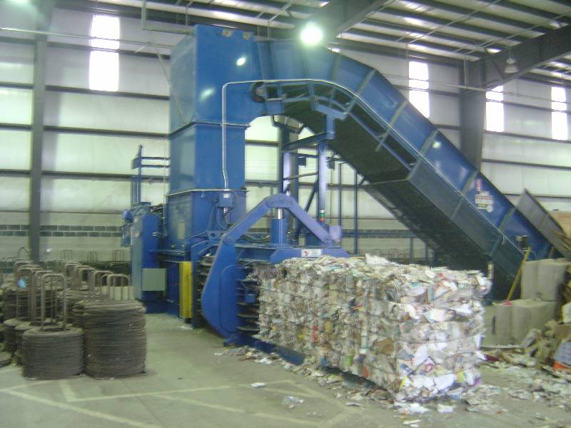 A conveyer belt is moving trash in an industrial facility.