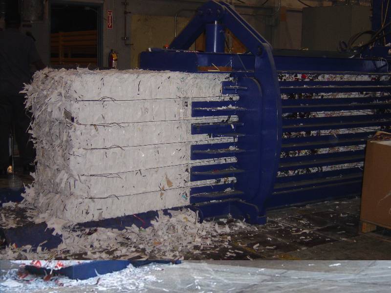 A large blue machine is loading white bricks.