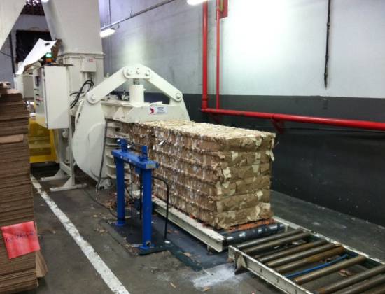 A machine that is loading boxes on to the conveyor belt.
