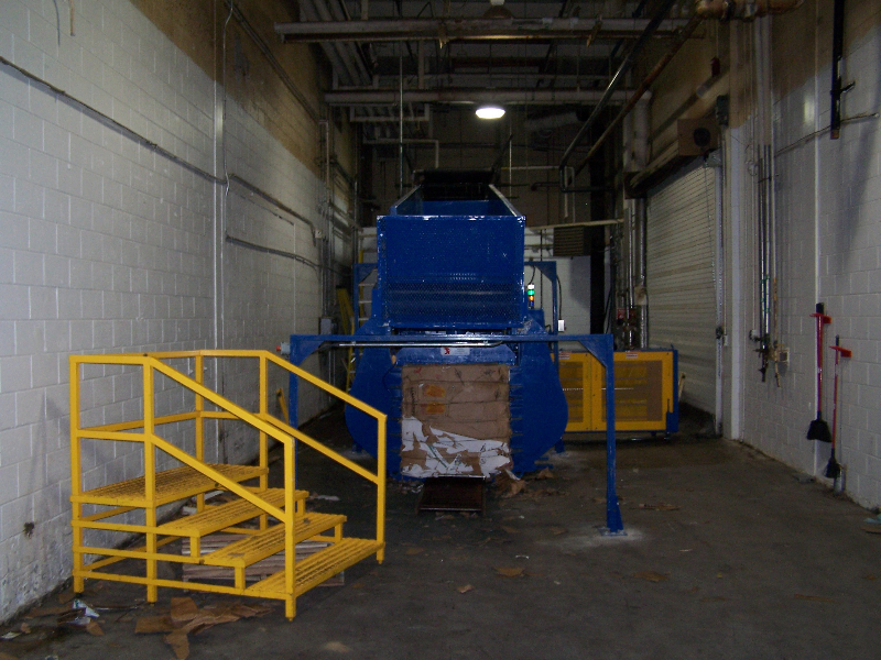 A blue machine in an industrial building with yellow stairs.