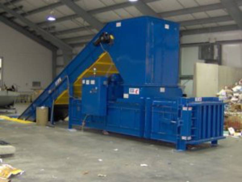 A blue machine is in the middle of a warehouse.