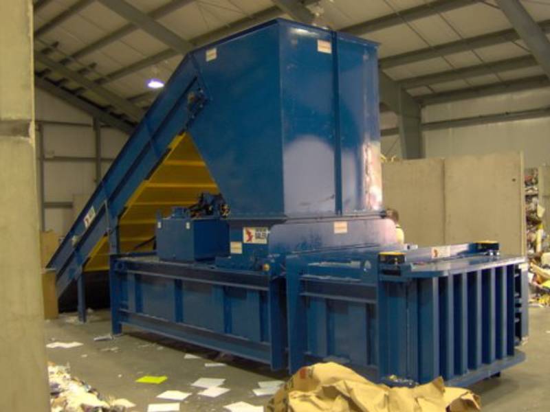 A large blue machine in a warehouse filled with papers.