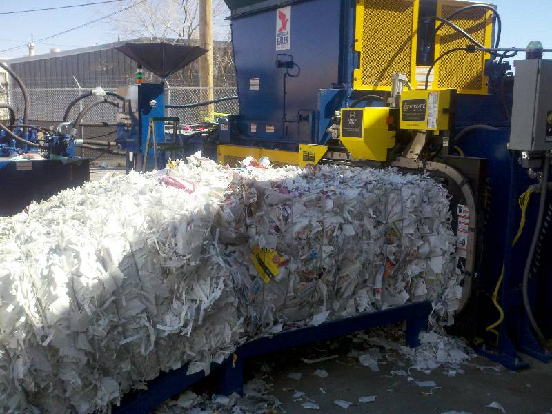 A large machine that is dumping paper into the ground.
