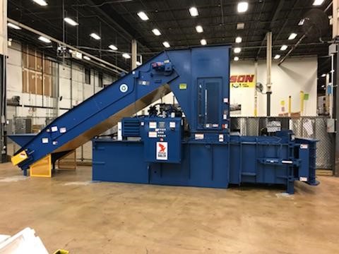 A large blue machine in a warehouse with a conveyor belt.