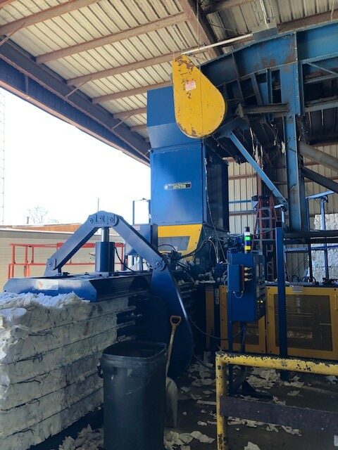 A blue and yellow machine is in the middle of an industrial area.