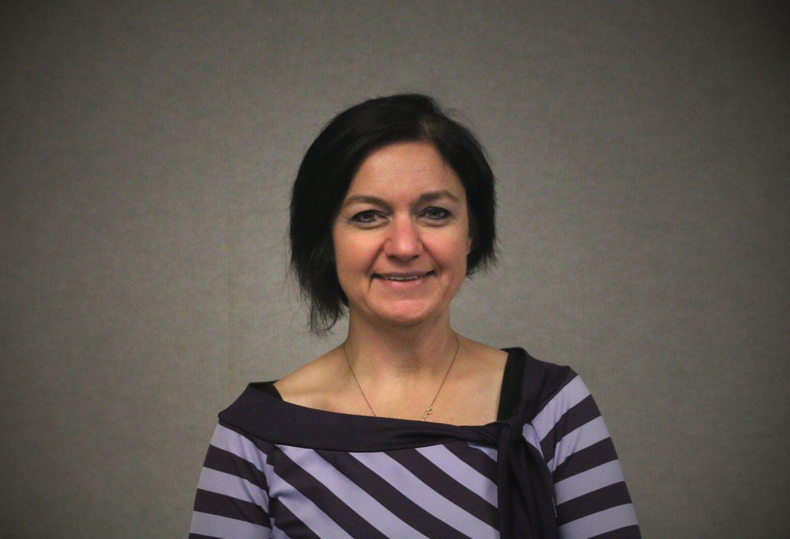 A woman with short hair and striped shirt.